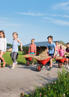 Niños ayudan con carretillas y cubos en FarmCamps De Smulhoeve en North Brabant, Países Bajos, en verano.