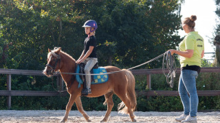 Un niño monta un pony bajo la supervisión de una instructora en FarmCamps Breehees, North Brabant, Países Bajos.