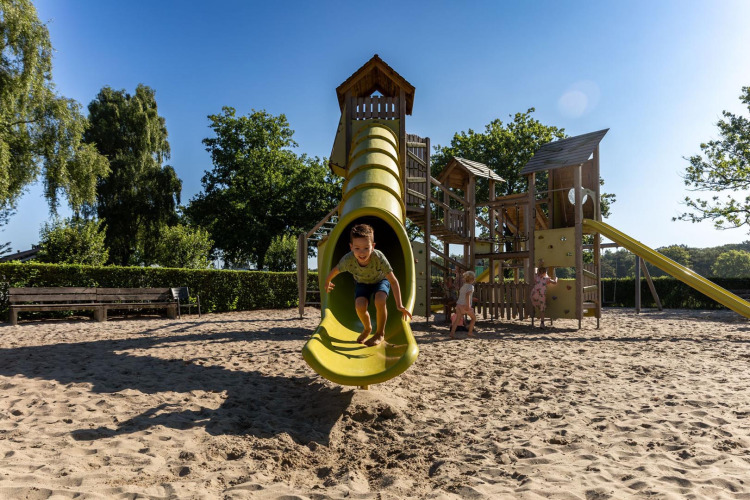 Kinder spielen auf einem großen Spielplatz mit Rutsche im Sand, FarmCamps Breehees, Nordbrabant, Niederlande.