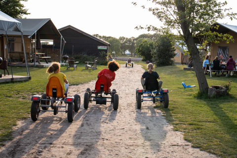 Niños montan en karts por un sendero de tierra en FarmCamps Breehees, parque vacacional en Brabante Septentrional.