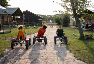 Kinder fahren Go-Karts auf einem Sandweg im Ferienpark FarmCamps Breehees in Nordbrabant, Niederlande.