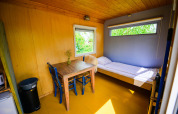 Interno della tiny house Pipowagen al Netl Camping Kallumaan, Paesi Bassi, con letto e tavolo.