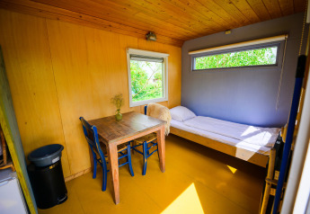 Interior of Pipowagen tiny house at Netl Camping Kallumaan, Netherlands, featuring bed and table.