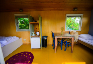 Interior de la tiny house Pipowagen en Netl Camping Kallumaan en los Países Bajos con camas y mesa.