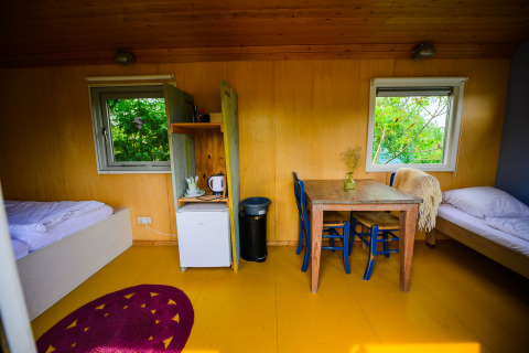 Intérieur de la tiny house Pipowagen à Netl Camping Kallumaan aux Pays-Bas avec lits, table et fenêtres.