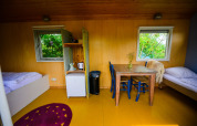Interior de la tiny house Pipowagen en Netl Camping Kallumaan en los Países Bajos con camas y mesa.