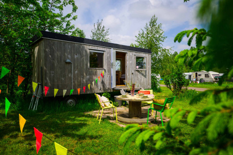 Pipowagen tiny house at Netl Camping Kallumaan in the Netherlands, decorated with colorful bunting flags.
