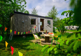 Das Pipowagen Tiny House bei Netl Camping Kallumaan in den Niederlanden, geschmückt mit bunten Wimpeln.
