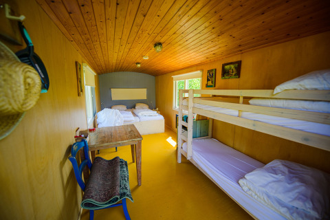 Interno di una tiny house con letti e tavolo al Pipowagen di Netl Camping Kallumaan, Paesi Bassi.