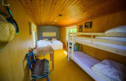 Interno di una tiny house con letti e tavolo al Pipowagen di Netl Camping Kallumaan, Paesi Bassi.