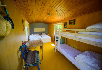 Interno di una tiny house con letti e tavolo al Pipowagen di Netl Camping Kallumaan, Paesi Bassi.