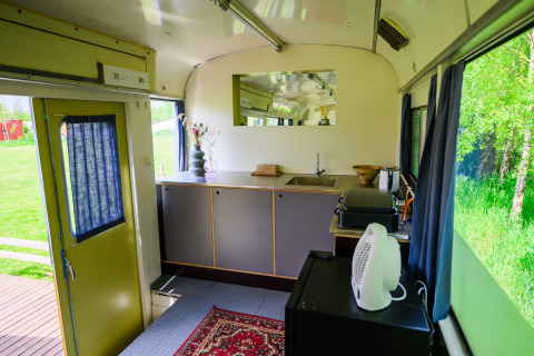 Binnenaanzicht van tiny house Streetcar bij Netl Camping Kallumaan in Nederland, met keuken en raamuitzicht.