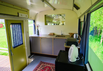 Binnenaanzicht van tiny house Streetcar bij Netl Camping Kallumaan in Nederland, met keuken en raamuitzicht.