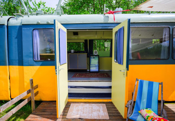 Streetcar tiny house ved Netl Camping Kallumaan i Holland med åbne døre og farverige udendørs detaljer.