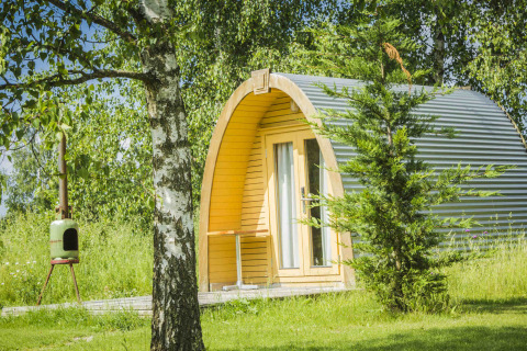 Cabaña en forma de pod en Netl Camping Kallumaan, Países Bajos, rodeada de árboles y césped verde.