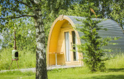 Cabaña en forma de pod en Netl Camping Kallumaan, Países Bajos, rodeada de árboles y césped verde.