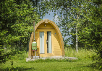 Eine rustikale Holzhütte namens Log Cabin bei Netl Camping Kallumaan in den Niederlanden inmitten von Bäumen.