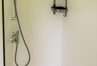 Douche minimaliste à Birdhouse, Netl Camping Kallumaan, Pays-Bas, avec étagère d’angle en acier inoxydable.