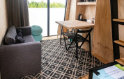 Acogedor interior de Birdhouse en Netl Camping Kallumaan, Países Bajos, con sofá, mesa y ventana grande.