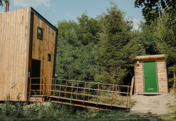 Kleines Holzhaus Birdhouse mit Rampe bei Netl Camping Kallumaan, umgeben von Bäumen in den Niederlanden.