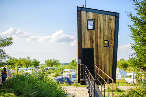 Modernes, schmales Tiny House namens Birdhouse bei Netl Camping Kallumaan mit Zelten in den Niederlanden.