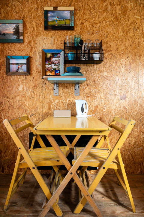 Petit coin repas avec table et chaises jaunes, décor mural et vaisselle dans une tiny house en conteneur aux Pays-Bas.