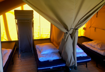 Interno della Lodge Compact al Camping de Tolbrug nei Paesi Bassi, con diversi letti singoli in una tenda.