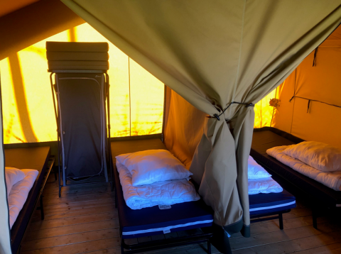 Innenraum der Lodge Compact auf Camping de Tolbrug, Niederlande, mit mehreren Einzelbetten in einem Zelt.