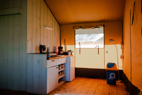 Binnenkant van safaritent met keukentje en vuilbak bij Camping De Rammelbeek, Nederland.
