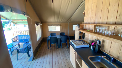 Vista interna di una tenda Safari con cucina, tavolo da pranzo e terrazza al Camping de Tolbrug, Olanda.