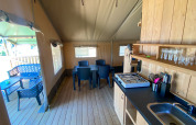Vista interna di una tenda Safari con cucina, tavolo da pranzo e terrazza al Camping de Tolbrug, Olanda.