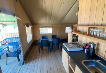 Vista interna di una tenda Safari con cucina, tavolo da pranzo e terrazza al Camping de Tolbrug, Olanda.