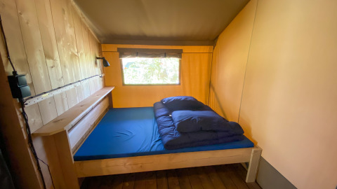 Habitación sencilla dentro de una tienda safari en Camping de Tolbrug, Países Bajos, vista interior.