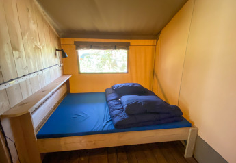 Binnenzicht van een eenvoudige slaapkamer in een safaritent bij Camping de Tolbrug, Nederland.