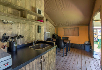 Interiør af Safari-telt med køkken, spisebord og trædæk på Camping De Rammelbeek, Holland.