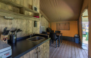 Innenraum eines Safari-Zeltes mit Küchenbereich, Esstisch und Holzfußboden in Camping De Rammelbeek.