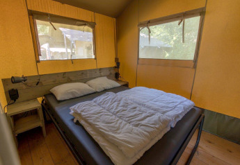 Interieur van een safaritent met tweepersoonsbed en ramen bij Camping De Rammelbeek, Nederland, comfortabel.