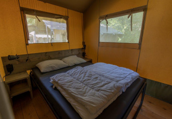 Interno di una tenda safari con letto matrimoniale e finestre al Camping De Rammelbeek, Paesi Bassi, accogliente.