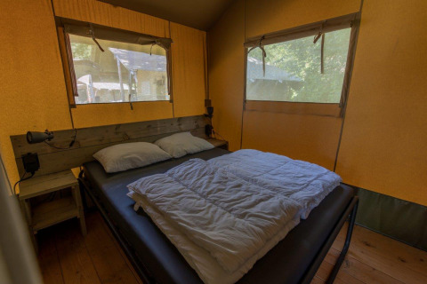 Interieur van een safaritent met dubbel bed en ramen op Camping De Rammelbeek, Nederland, gezellig en licht.