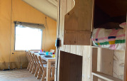 Interieur van een safaritent bij Minicamping Hofstede Zonnevliet met houten meubelen en beddengoed.