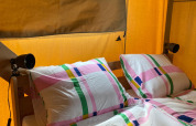 Interior view of a safari tent with colorful bedding and sanitary facilities at Minicamping Hofstede Zonnevliet.