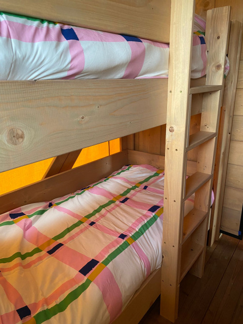 Literas con ropa de cama colorida en una tienda safari en Minicamping Hofstede Zonnevliet, Países Bajos.