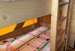 Bunk beds with colorful checkered bedding inside a safari tent at Minicamping Hofstede Zonnevliet, Netherlands.