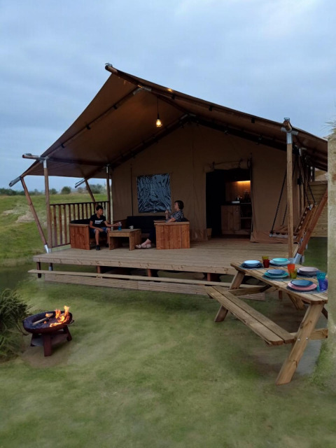 Safari telt med terrasse og bålplads på Minicamping Hofstede Zonnevliet i Holland, gæster slapper af.