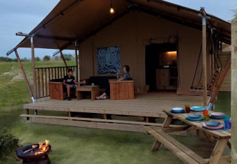 Safari telt med terrasse og bålplads på Minicamping Hofstede Zonnevliet i Holland, gæster slapper af.