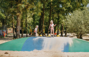 Kinder spielen auf einem großen Hüpfkissen im Sand im Ferienpark Camping De Rammelbeek, Overijssel.