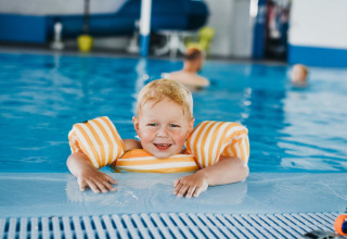 Bambino con braccioli si diverte nella piscina coperta del Camping De Rammelbeek a Overijssel, Paesi Bassi.