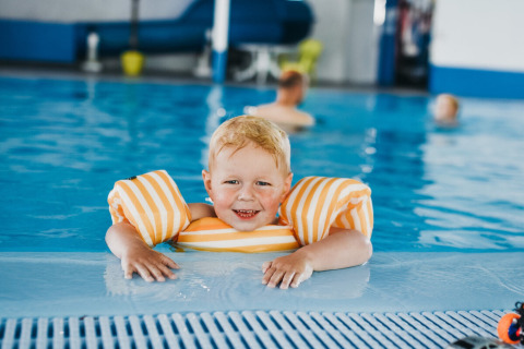 Jeune garçon avec brassards gonflables profite de la piscine intérieure au Camping De Rammelbeek, Overijssel.
