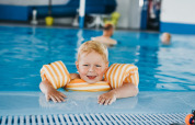 Lille dreng med svømmevinger nyder de indendørs poolfaciliteter på Camping De Rammelbeek i Overijssel.
