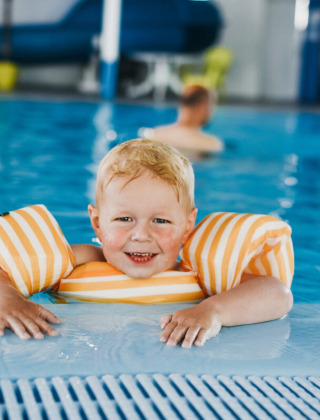 Niño pequeño con manguitos disfruta de la piscina cubierta en Camping De Rammelbeek, Overijssel, Países Bajos.